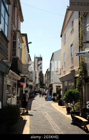 The shops along Foss Street in the Devon town of Dartmouth with the church of St Saviour's in the background. Stock Photo