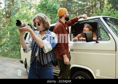 Young woman photographing the nature while travelling by car with her friends Stock Photo