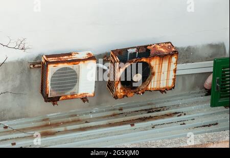Two old rusted air conditioners on the white wall on the house Stock Photo