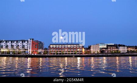 calm dusk evening in the town reflection on the water, still city at night, moon light reflected on the water. Stock Photo