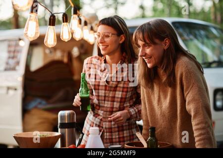 Two young women drinking beers and having fun outdoors on a picnic Stock Photo