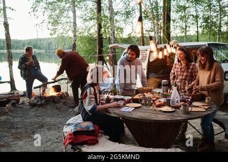 Group of friends eating and talking together on a picnic in the forest Stock Photo