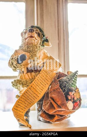 Vintage bear Santa Father Christmas decoration in with bag of toys and long list in front of frosty window with light coming in - Selective focus. Stock Photo