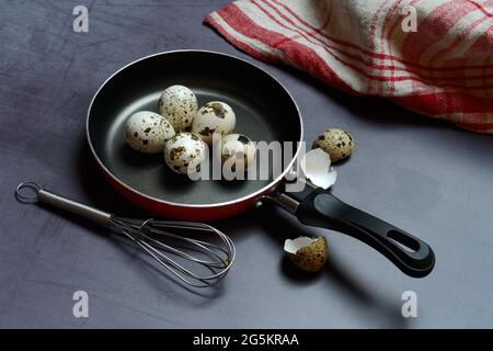 Quail eggs in frying pan and whisk Stock Photo