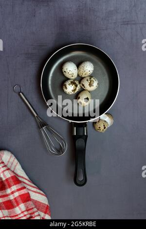 Quail eggs in frying pan and whisk Stock Photo
