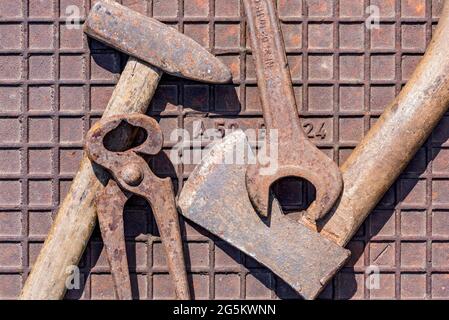 Old tool with hammer, wrench, pliers, axe on rusty iron plate, Germany, Europe Stock Photo