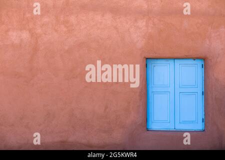 Abstract image of blue window and red adobe wall, Taos, New Mexico Stock Photo