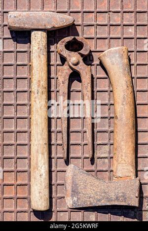 Old tool with hammer, pliers, axe on rusty iron plate, Germany, Europe Stock Photo