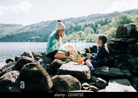 mom cooking on a portable cooker whilst camping with her son Stock Photo