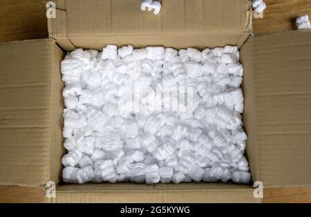 A cardboard box with packing foam top view, Delivery box for fragile product on wooden table Stock Photo