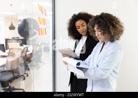 Multicultural coworkers using white board and doing brainstorming together. Co-working concept Stock Photo