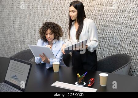 Young business woman working in the office with her coworker and doing paperwork. Stock Photo