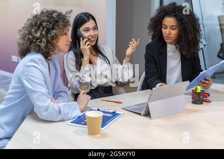 business women having a reunion in the office and looking at paperwork. Stock Photo