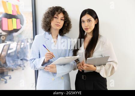 Young and pretty business women working in an office. They are smiling and looking at camera. Stock Photo