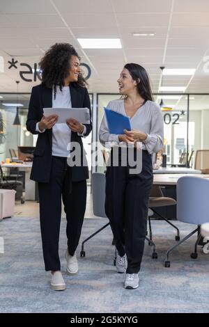 Multicultural coworkers walking in the office and having a conversation. Stock Photo