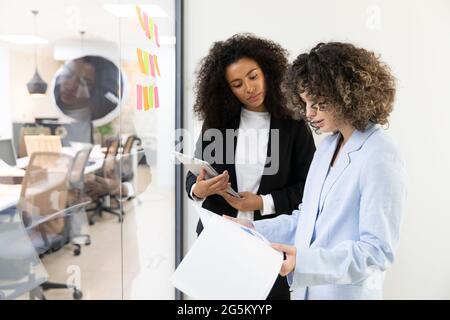 Multicultural coworkers using white board and doing brainstorming together. Co-working concept Stock Photo