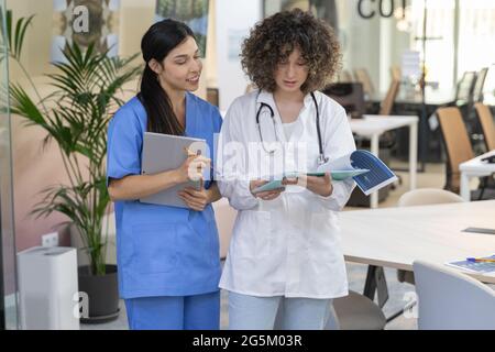 Concentrated female doctor with curly hair talking with a nurse and ...