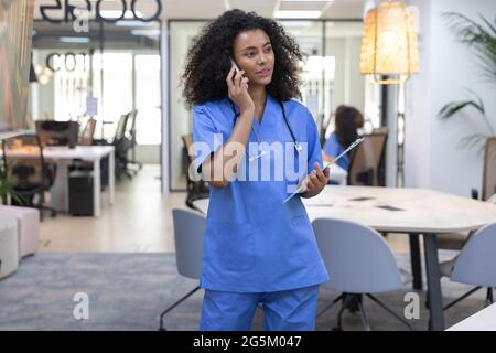 Young african american nurse wearing blue uniform talking on the phone and looking at camera. Stock Photo