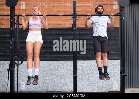 Young man and woman doing pull ups at a crossfit pull up bar Stock Photo