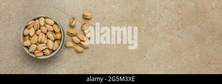 Pistachio top view. Pistachios in a saucer on a marble stone table top. Banner for website header, design or print. Stock Photo