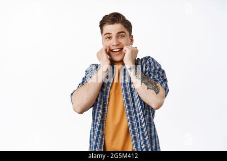 Image of surprised and excited young man, real emotions of happiness and disbelief, guy receive big awesome news, surprise gift, standing amazed Stock Photo