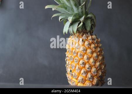 Pineapple is a tropical plant with an edible fruit and the most economically significant plant in the family Bromeliaceae. Shot on black background Stock Photo