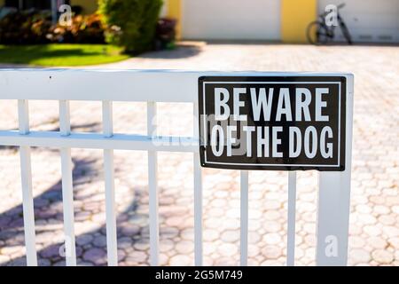 Beware of the dog sign on white fence gate railing in residential neighborhood house home in Hollywood, Florida Broward County North Miami Beach Stock Photo