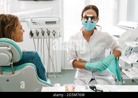 European mid dentist woman in face mask using microscope while working in dental clinic Stock Photo
