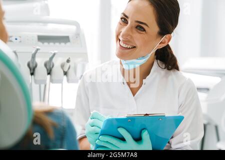European mid dentist woman smiling while working with patient in dental clinic Stock Photo