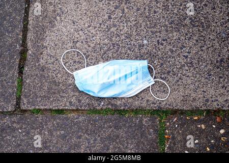 Discarded disposable face mask dropped on pavement Stock Photo