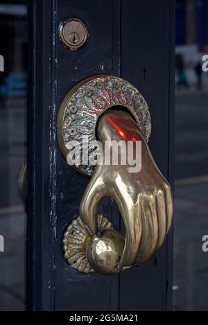 Brass door handle in the shape of a hand opening a door, Edinburgh, Scotland, UK. Stock Photo