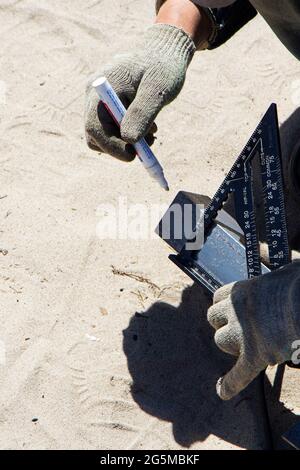 A worker marks the cut line on a piece of metal. Stock Photo