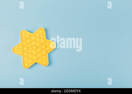 New silcone toy pop it in shape of star on the blue background. New sensory anti-stress toy for children and adult. Copy space. Flat lay. Stock Photo