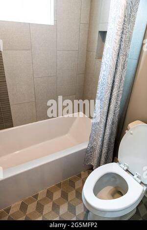 Modern bathroom interior with decorative tiled shower tub in contemporary home, apartment or house with toilet and curtains Stock Photo