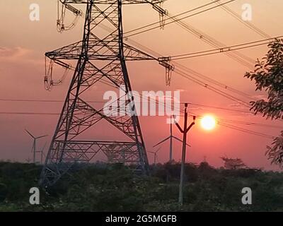 High voltage electric towers and windmills in the sun and sky background Stock Photo