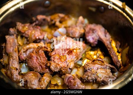 Cooked lamb meat shoulder chops chucks cut in frying pan and onions to make traditional Kazakh or Uzbek pilaf or plov macro closeup Stock Photo