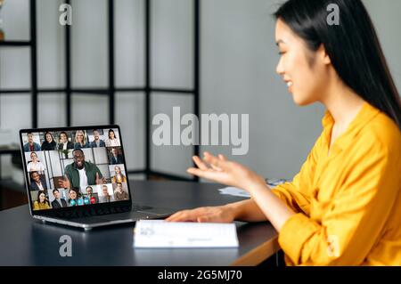 Online business meeting, brainstorm of employees. Asian successful young woman talking on video conference with colleagues of different nationalities, discussing the project. Online conversation Stock Photo