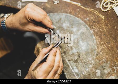 Jeweler working in his workshop placing a gem on a gold ring Stock Photo