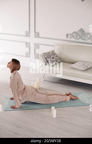 Young lady starting morning with yoga exercises in bedroom Stock Photo