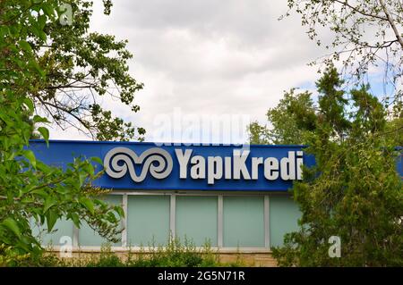 Ankara Turkey. June 2021. The signboard of YapiKredi Bank among trees. Founded in 1944, is one of the biggest banks in Turkey. Dynamic Ram head logo.  Stock Photo