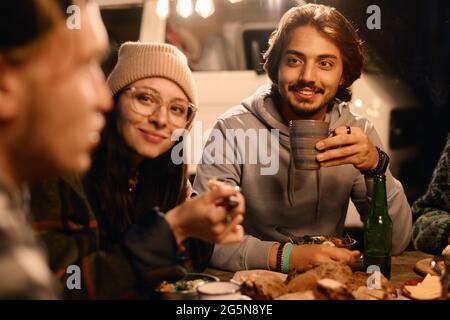 Group of young people sitting at the table and having dinner together outdoors Stock Photo