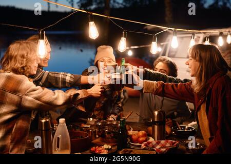 Group of young friends toasting with drinks and having fun during picnic on the nature Stock Photo