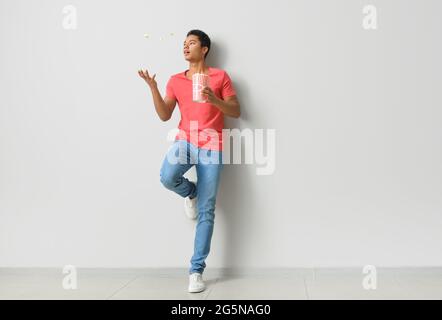 African-American teenager with popcorn near light wall Stock Photo