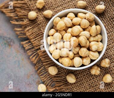 Peeled hazelnuts in a bowl on grey concrete background Stock Photo