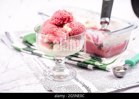 Strawberry frozen yogurt in glass bowl, ice cream balls, container with homemade sundae Stock Photo