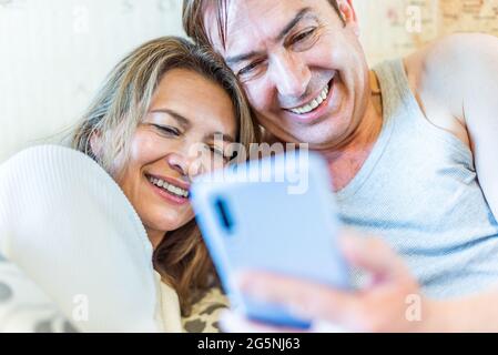 Happy middle-aged couple looking at mobile smiling. Stock Photo