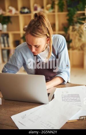 Focused female florist typing on her laptop Stock Photo