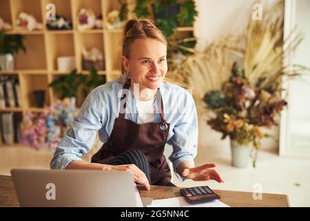 Happy floral designer in casual clothes working in the flower shop Stock Photo