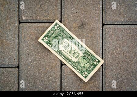 One dollar banknote lying on the ground. Lost money. Stock Photo