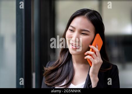 Close up asian business woman making a phone call and smiling at office Stock Photo